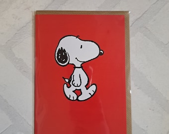 Può includere: Un biglietto d'auguri rosso con un'illustrazione in bianco e nero di Snoopy, un beagle dei cartoni animati, in piedi sulle zampe posteriori.
