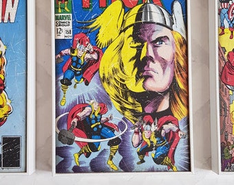 May include: A vintage comic book cover featuring Thor, the Mighty, in a red and yellow costume. The cover is framed in white and has a blue background with the text "The Mighty Thor" and "Marvel Comics Group" printed on it.