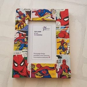 Peut inclure: Un cadre photo rectangulaire décoré de bandes dessinées de Spider-Man. Le cadre mesure 15 x 23 cm et possède un intérieur blanc pour une photo. Le design du cadre comprend du texte et des illustrations colorées.