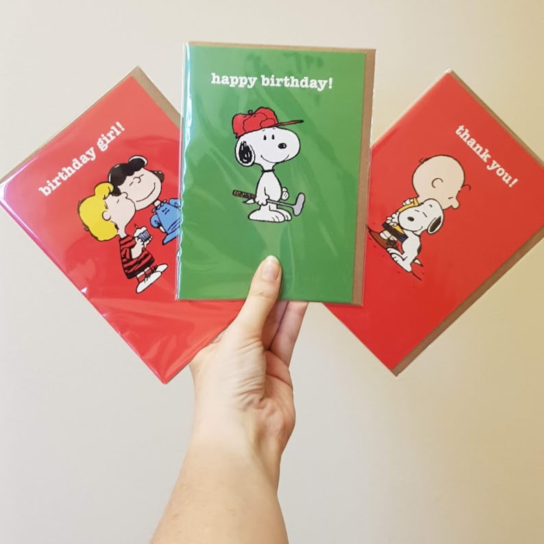 May include: Three greeting cards featuring Peanuts characters. One card says "happy birthday!" with Snoopy in a red cap. Another says "birthday girl!" with Lucy and a friend. The third says "thank you!" with Charlie Brown and Snoopy.
