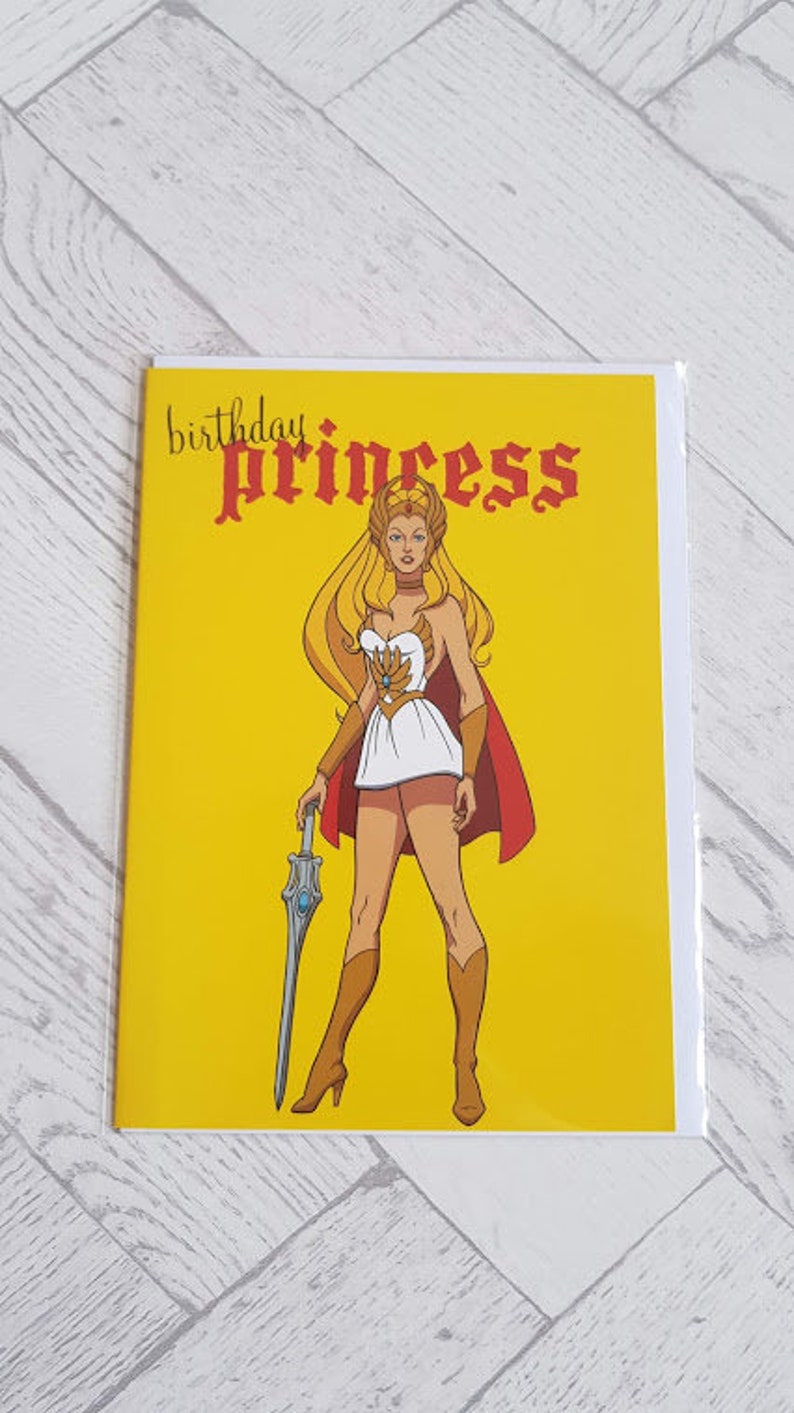 May include: A yellow card with the text "birthday princess" in red and black lettering. A cartoon image of a woman with blonde hair, wearing a white dress and holding a sword, is on the card.