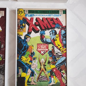 Op de afbeelding: Een vintage comicboekomslag met de X-Men. De omslag is vergeeld en versleten door de tijd. De titel "X-Men" staat in rode en witte letters. De tekst "At Last - The Spectacular 100th Issue of..." is gedrukt in rood en wit. De omslag toont een groep superhelden in actieposes. De personages zijn getekend in een klassieke comicboekstijl.