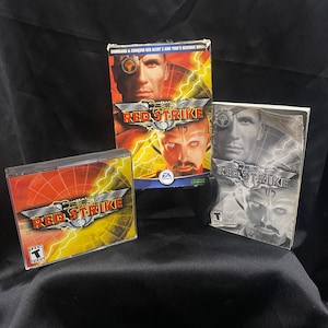 May include: Three game cases for the video game Command & Conquer: Red Strike. The cases are red, yellow, and black with the game title and a picture of a soldier on each.