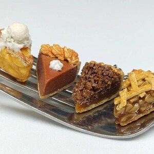 Puede incluir: Pequeñas porciones de pastel en un tenedor plateado. Las porciones incluyen un pastel de queso con helado, un pastel de chocolate con crema batida, un pastel de nueces y un pastel de manzana con corteza de rejilla. Los postres son detallados.
