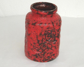 Puede incluir: Un jarrón de cerámica rojo y negro con una superficie texturizada. El jarrón tiene una forma cuadrada y una abertura ancha.