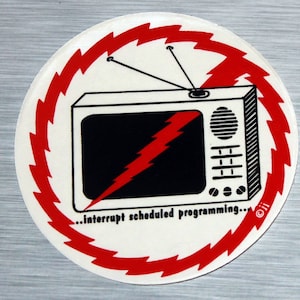 May include: A red and white sticker with a black and white television set in the center. The television has a lightning bolt on the screen and the text "...interrupt scheduled programming..." below it.