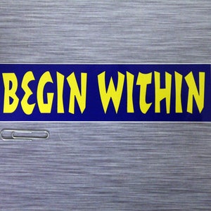 May include: A blue and yellow bumper sticker with the text "BEGIN WITHIN" in a bold, stylized font.