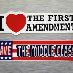 May include: Two bumper stickers. The top sticker reads "I ❤️ THE FIRST AMENDMENT" with a red heart. The bottom sticker says "SAVE THE MIDDLE CLASS" with a red, white, and blue design.