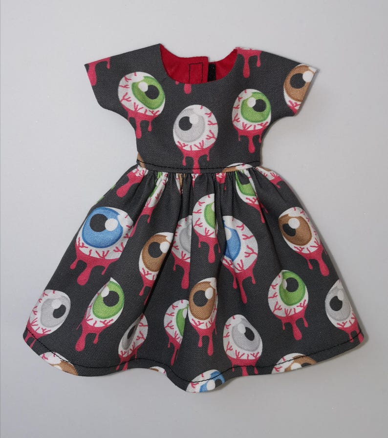 May include: A black dress with a pattern of colorful eyeballs with red dripping blood. The dress has short sleeves and a round neckline.