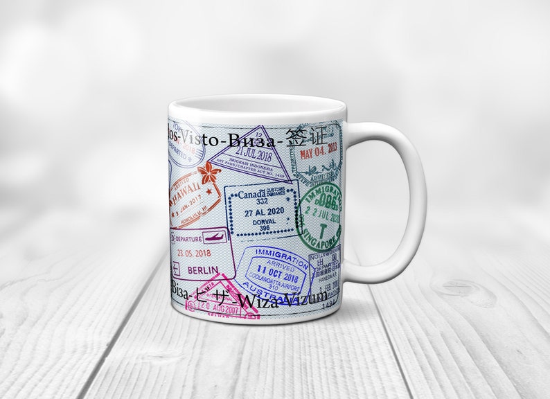 May include: White ceramic mug with a design of various passport stamps from different countries, including Hawaii, Canada, Singapore, and Berlin. The text "Visto-Bиза-签证" is printed on the mug.