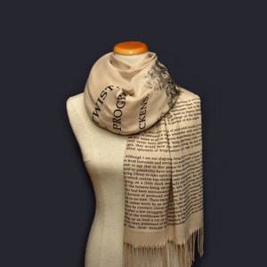 May include: A beige scarf with black text printed on it. The text is from the book "Oliver Twist" by Charles Dickens. The scarf has fringe on the ends.