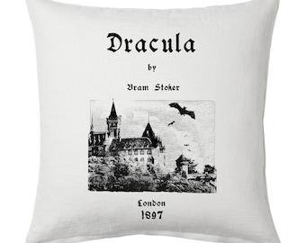 May include: A white pillow with black text that reads "Dracula by Bram Stoker" and a black and white illustration of a castle and bats. The text also includes "London 1897".