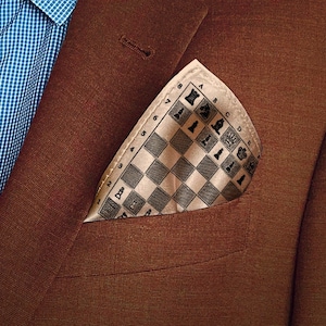 Könnte beinhalten: Ein brauner Blazer mit einem beigefarbenen Einstecktuch mit einem schwarz-weißen Schachbrettmuster. Das Einstecktuch hat die Zahlen 1 bis 8 und die Buchstaben A bis D aufgedruckt.