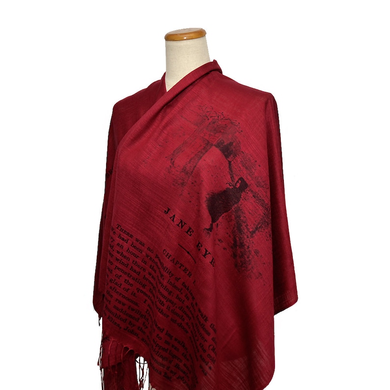 May include: A red scarf with a black print of the text "Jane Eyre" and a silhouette of a woman. The text includes the chapter number and a passage from the book.