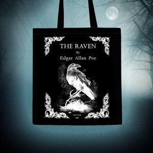 May include: Black tote bag featuring a white illustration of a raven and the text "THE RAVEN" by Edgar Allan Poe. The illustration is surrounded by ornate white flourishes.