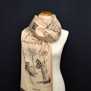 May include: A beige scarf featuring a black and white illustration from a Jane Austen novel. The scarf displays the title "Northanger Abbey" and the author's name. The design includes a scene of two women under trees. The scarf is draped on a mannequin.