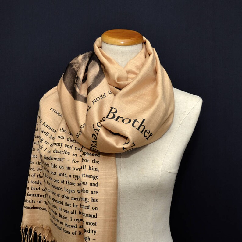 May include: A beige scarf with black text printed on it. The text reads "Brother" and includes a quote from Fyodor Dostoevsky's "The Brothers Karamazov".