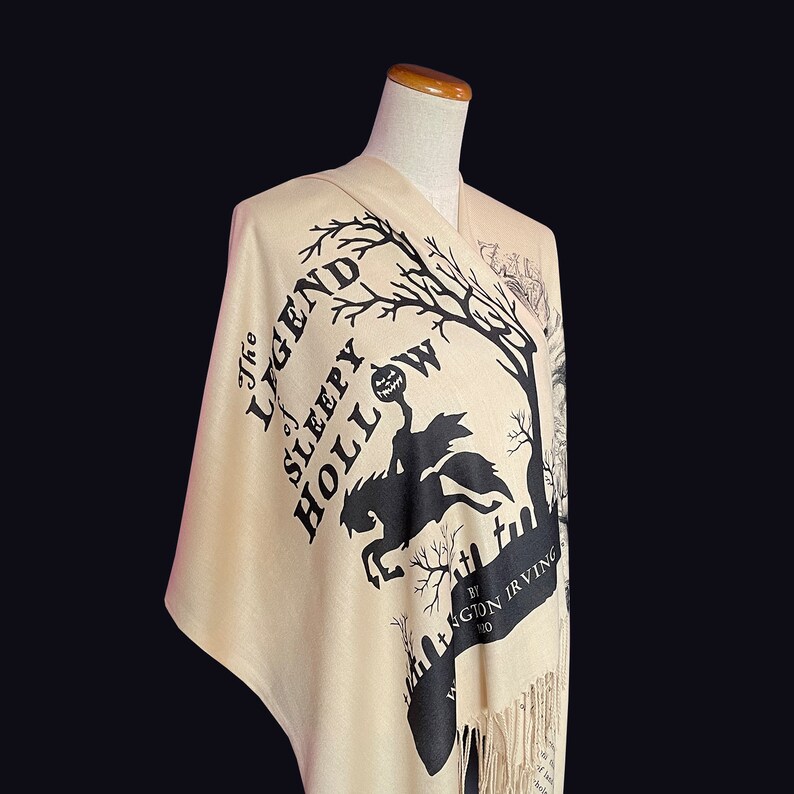 May include: A beige shawl with black text and a silhouette of a man riding a horse. The text reads "The Legend of Sleepy Hollow by Washington Irving".