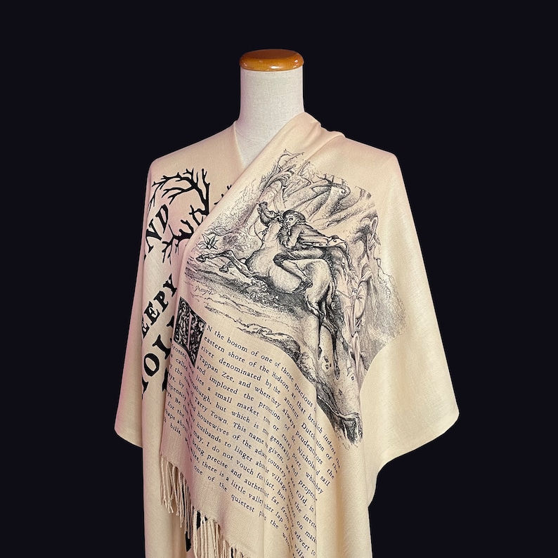 May include: A beige shawl with black text and an illustration of a man riding a horse. The text reads "In the bosom of one of those spacious eastern shore of the Hudson, that river denominated by the ancient Dutch of the Tappan Zee, and when hay sways prudently the wind, a small market is or was kept, and to which the good people of the neighbouring country would resort to dispose of their produce, and to buy town this name given to it, properly belongs to the little adjacent village, for the housewives of the town, as the old inhabitants do not linger about the fair, and indeed, there is no such village, for the simple reason that there is a little valley, in the bosom of which, and further up the river, is the quietest the"