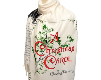 May include: Cream-colored scarf featuring the title "A Christmas Carol" in red, with green holly illustrations. The scarf includes text from the book and the author's name, Charles Dickens.
