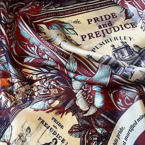 May include: A cream-colored silk scarf with a burgundy and blue floral pattern. The scarf features the text "Pride and Prejudice" and "Pemberley" in a vintage font.