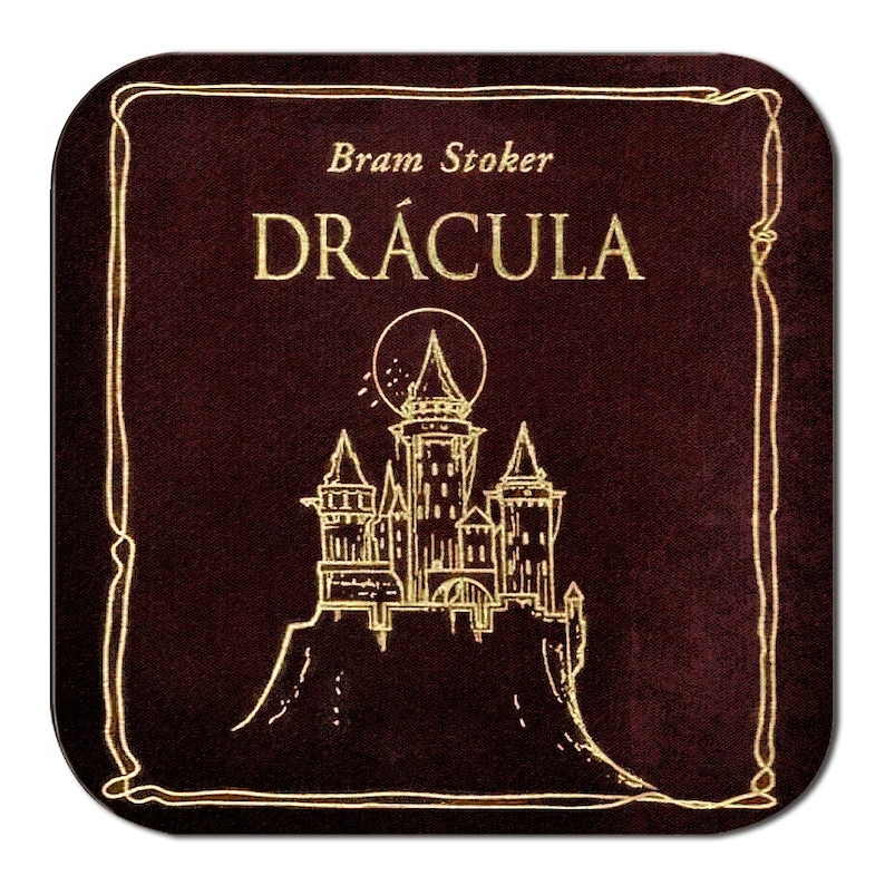 May include: Square coaster with a dark burgundy background and a gold border. The coaster features the title "DR&Aacute;CULA" in gold lettering, with the author's name, "Bram Stoker," above. A gold illustration of a castle is also present.