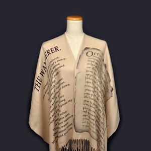 May include: A beige shawl with black text printed on it. The text reads "The Wanderer" and "Oft" with a poem printed on the shawl.