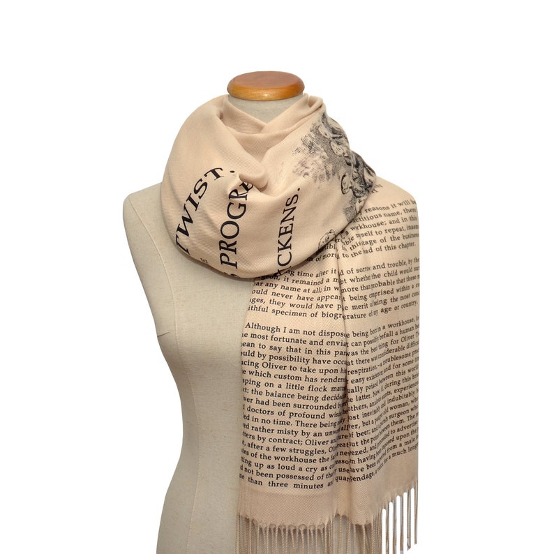 May include: A beige scarf with black text from Charles Dickens's "Oliver Twist" printed on it. The text reads "PROGRESSIVE" and "PICKENS".