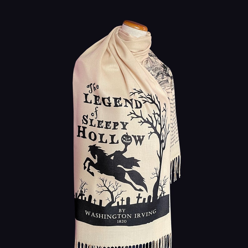 May include: A beige scarf with black text and a silhouette of a headless horseman riding a horse. The text reads "The Legend of Sleepy Hollow" by Washington Irving 1820.