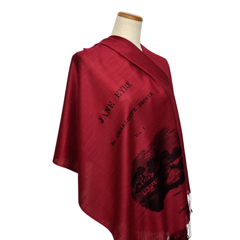 May include: A red silk scarf with a black print of the book cover for "Jane Eyre" by Charlotte Bronte. The cover features the title, author, and volume number.