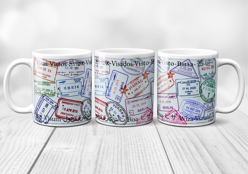 May include: Three white ceramic mugs with a design of passport stamps from various countries. The stamps are in different colors and languages, including "Visas", "Vistos", "Visto", "Visa", and "签证".