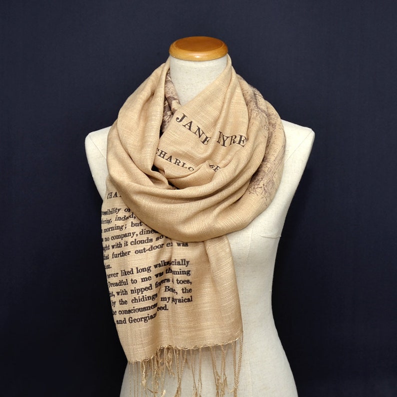 May include: A beige scarf with a brown printed excerpt from Jane Eyre. The scarf has a fringe on the bottom.