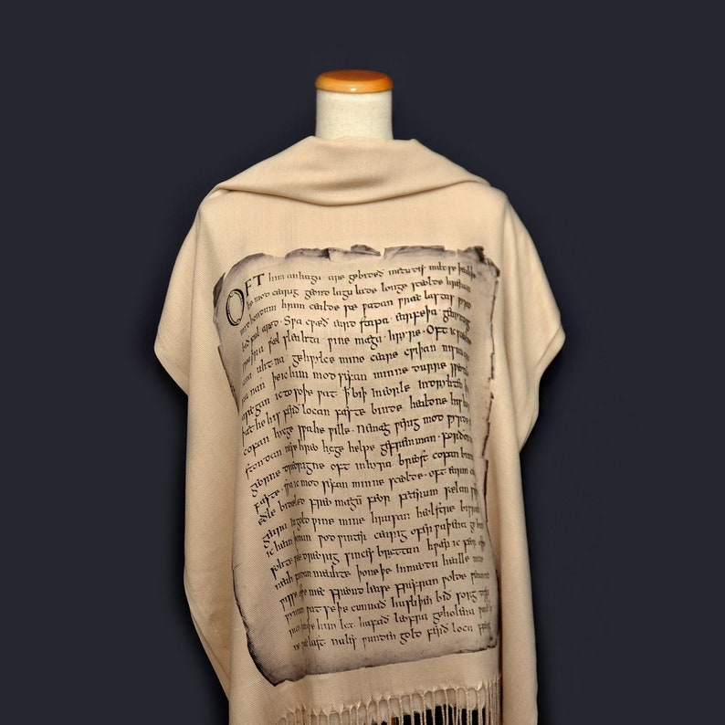 May include: A beige shawl with a black printed inscription in an old-fashioned font. The inscription reads "Oft inunsnagu, upe geberes, incusut midge fell, lewes alque, gdro lagy lewze poble, hyun chloe yutuan phat layo, -Spaced the papa tapper, opel ploutras pine mazu hope Ofek, ab phrice ine clape chan, eselum mov ppaan mmne vuppe, gagun iewpole pur Fort Intople Invorh, het the type locan parco brmee hrone, copan huge pahe pillo-Niinag pins, applied meanupils adyay Soly only ane ema sungl, ld com, sopno izne ope imhopa bridge copan, pipan minne postve of m, surd andered word smu qult spany ones, ppine mine, hatan po pi&eta;&tau;ή&sigmaf; &omicron;&lambda;&iota;&gamma;&epsilon;&sigmaf; &sigma;&kappa;ί&zeta;n partha gi, &mu;ί&alpha; &mu;&omicron;&tau;ό&mu;&epsilon;&sigmaf; &gamma;inety onerrun hướn, pagesepibus litape prijepan polve p, phim les lapas libppa geholtina p, osa naly purvih zote pijid loca ait."