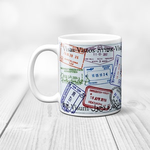 May include: White ceramic mug with a design of various passport stamps and the text "Visas Vistos-שרות-Vist" printed on it.