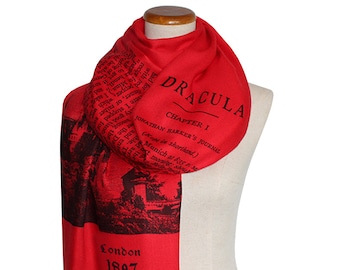 May include: Red scarf with a black and white print of the cover of the book Dracula by Bram Stoker. The print includes the title, chapter one, and the author's name. The scarf also has the text "London 1897" printed on it.
