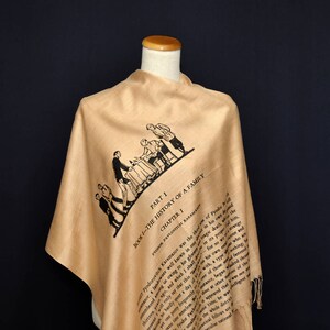May include: A beige silk scarf with a black and white illustration of people sitting at a table. The scarf has text printed on it that reads "Part I Book I - The History of a Family Chapter 1 Fyodor Pavlovich Karamazov was the..."