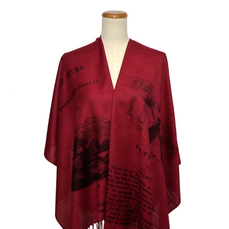 May include: A red shawl with a black print of a book cover and text that reads "Jane Eyre" by Charlotte Bronte. The text is from the book and includes a quote from the story.