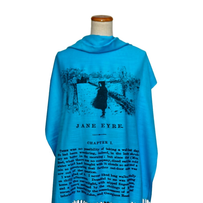 May include: A turquoise blue scarf with a black and white image of a girl walking in a snowy landscape. The scarf has the text "Jane Eyre" and "Chapter I" printed on it.