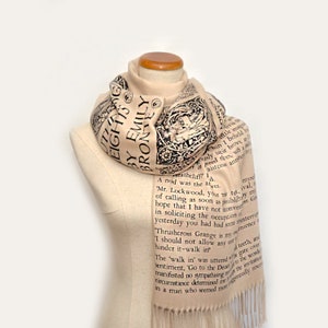 May include: A beige scarf with black text printed on it. The text is from the book "Wuthering Heights" by Emily Bronte. The scarf has fringe on the ends.