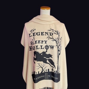 May include: A beige shawl featuring a black print of the text "The Legend of Sleepy Hollow" by Washington Irving, 1820. The print also includes a silhouette of a headless horseman riding a horse.
