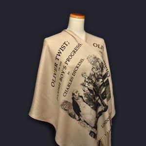 May include: A beige scarf with a black print of the book cover for "Oliver Twist" by Charles Dickens. The print includes an illustration of characters from the book.