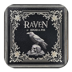May include: Square black coaster featuring the title "RAVEN" by Edgar A. Poe. A silver raven is perched atop a skull. The border and text are in silver, with ornate scrollwork. The coaster has a textured appearance.
