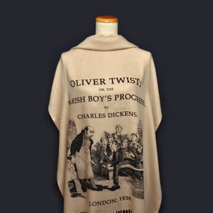 May include: A beige scarf with a black and white illustration of a scene from the book "Oliver Twist" by Charles Dickens. The text on the scarf reads "Oliver Twist, Or, The Parish Boy's Progress. By Charles Dickens. London: 1838."