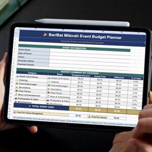 May include: A digital tablet showing a Bar/Bat Mitzvah Event Budget Planner. The screen displays a detailed spreadsheet with categories for event costs, including catering and decorations. A stylus rests on top of the tablet.