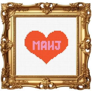 May include: A framed cross-stitch artwork featuring a pixelated orange heart with the letters "MAHJ" in pink. The artwork is set within an ornate, gold-colored frame, creating a classic and decorative aesthetic.