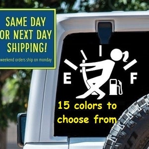 May include: White car decal with a gas gauge graphic and a stick figure holding a gas can. The text "15 colors to choose from" is below the graphic. The decal is on the back of a white Jeep.