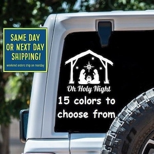 May include: White vinyl decal of a nativity scene with the text "Oh Holy Night" and "15 colors to choose from". The decal is on the back window of a white Jeep.