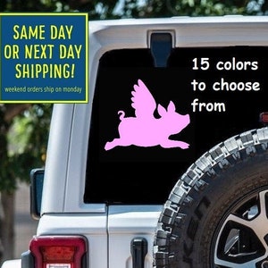 May include: Pink flying pig silhouette decal sticker for a car. The decal is on the back window of a white Jeep. The text on the decal says "15 colors to choose from".