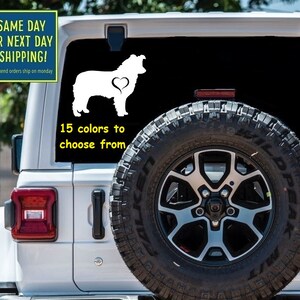 May include: White vinyl decal of a dog with a heart on its side, displayed on a vehicle window. The text "15 colors to choose from" is below the dog. The image also includes the text "SAME DAY OR NEXT DAY SHIPPING!"
