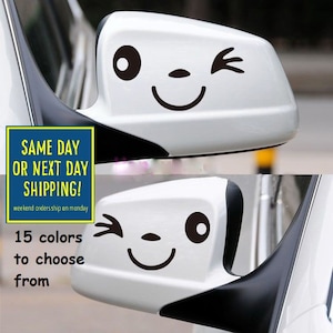 May include: A white car with a black and white smiley face sticker on the side mirror. The sticker is winking. The text on the image reads "SAME DAY OR NEXT DAY SHIPPING! weekend orders ship on monday 15 colors to choose from".